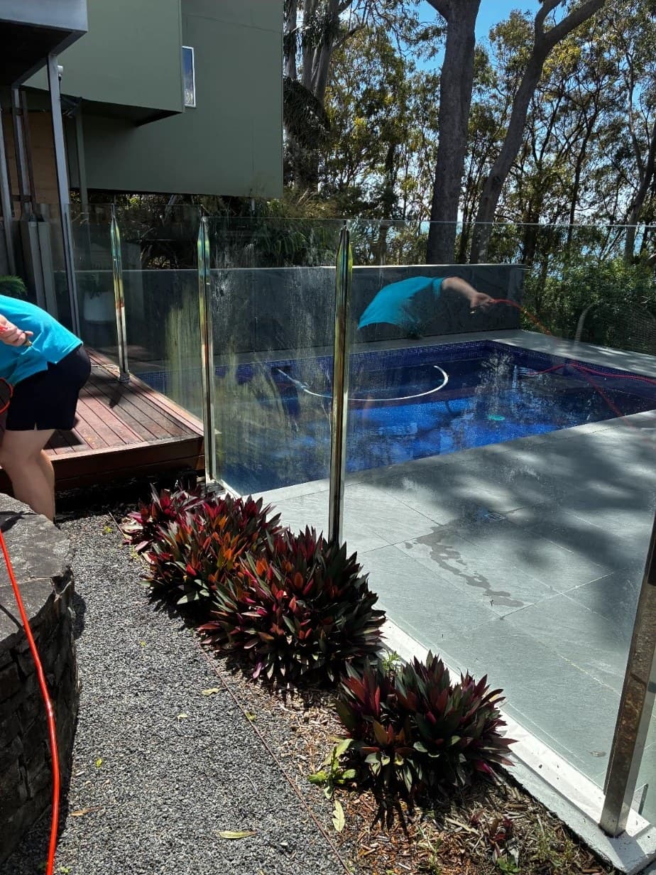 Pool fence glass halfway through a Squeegee Bros clean, still wet
